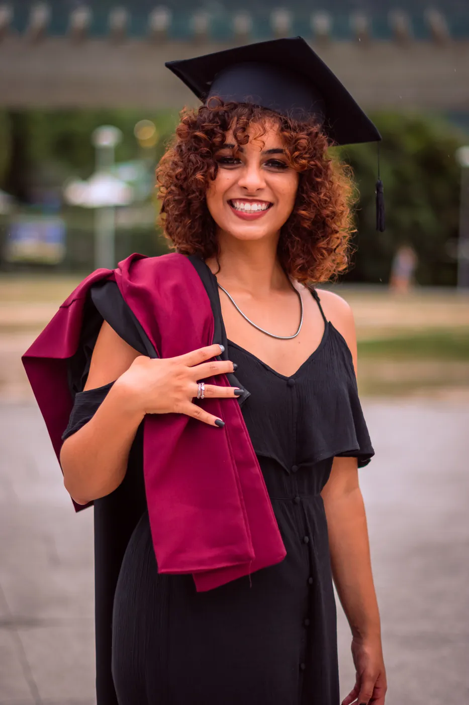 Formanda sorrindo ao ar livre com fundo verde e luz de tarde, ensaio externo