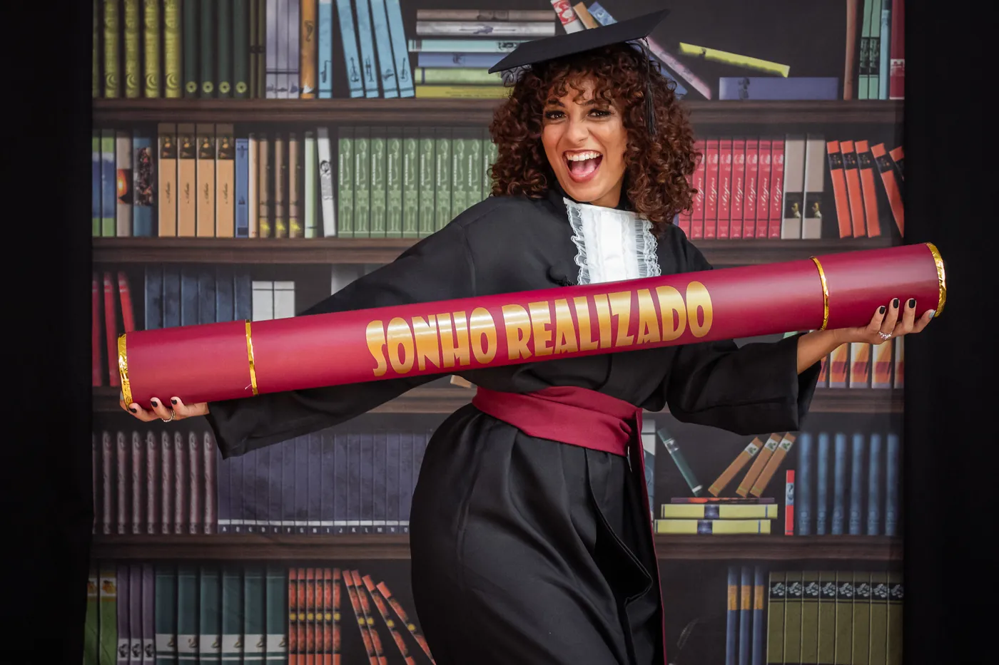 Retrato próximo de formanda emocionada segurando diploma, ensaio externo