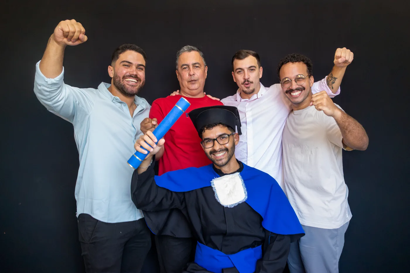 Formando comemorando com amigos e diploma em estúdio com fundo preto
